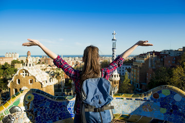mujer con mochila levantando los brazos mientras observa la ciudad de Barcelona desde un mirador