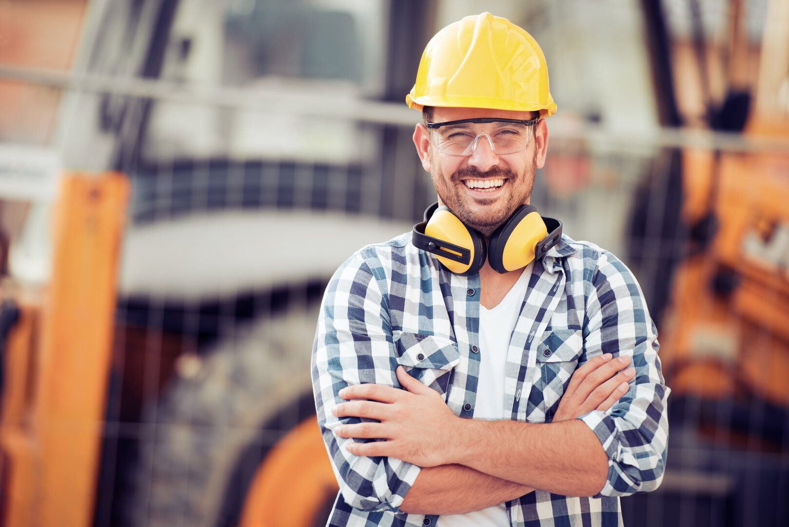 hombre con casco de seguridad y camisa de cuadros sonriendo en un entorno de trabajo industrial