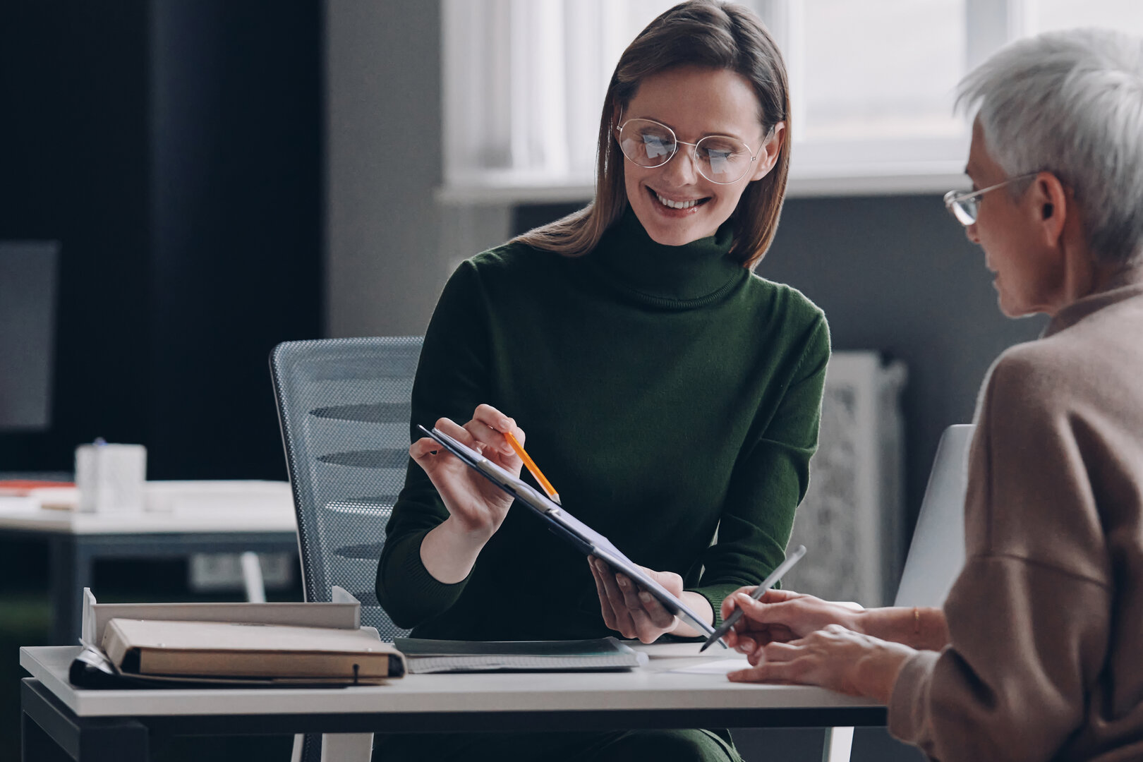 mujer y hombre conversando sonrientes mientras revisan documentos en una oficina moderna