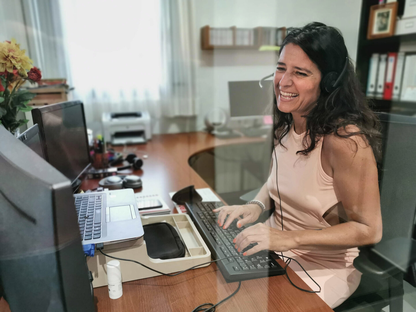 mujer sonriente trabajando en una oficina frente a un ordenador y documentos